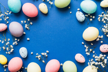 Happy Easter composition. Easter eggs on colored table with gypsophila. Natural dyed colorful eggs background top view with copy space