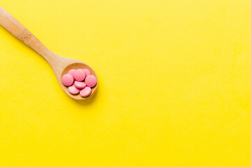 Vitamin capsules in a spoon on a colored background. Pills served as a healthy meal. Red soft gel vitamin supplement capsules on spoon