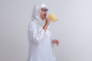 Asian girl standing and drinking water to break her fast, during Ramadan month