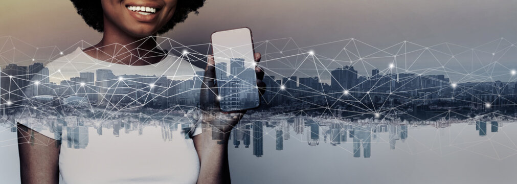 Portrait of cute happy african american woman holding smartphone with empty screen display against city background. Communication, technology, IoT, internet, global, network, futuristic concept - Powered by Adobe