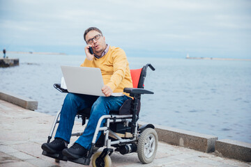 a special person with disabilities by the sea with a laptop