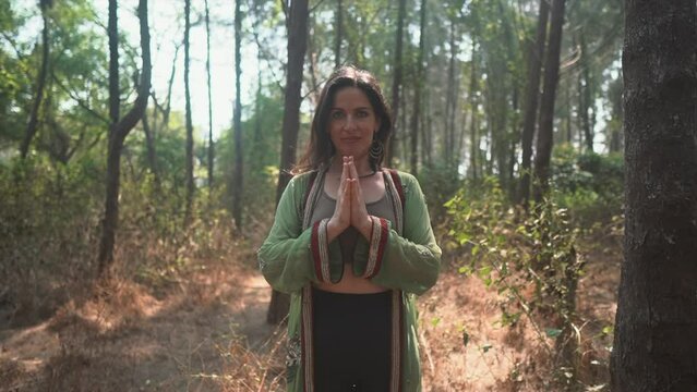 Positive spiritual brunette woman meditating in the forest, connecting with higher self