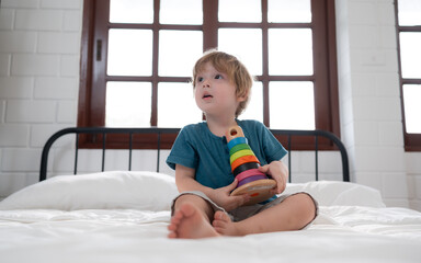 Fototapeta premium Little boy in his bedroom with a new toy purchased by his parents to help him improve his thinking skills.