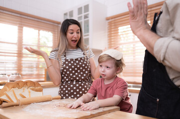 Fototapeta premium Mom and dad in the kitchen of the house with their small children. Have a good time baking bread and making dinner together.