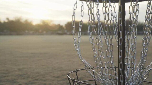 Disc Golf Putt Made into the Center Chains of a Frolf Basket during a Beautiful Sunset
