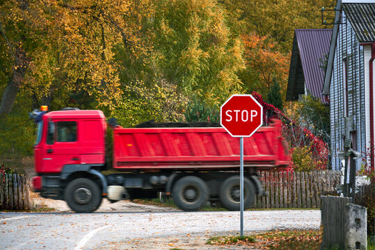 A Large Red Delivery Truck Driving Past A Stop Sign