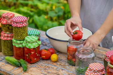 A woman preserves vegetables in jars. Selective focus.