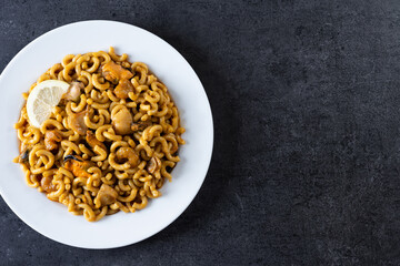 Traditional Spanish fideua. Noodle paella on black background. Top view. Copy space