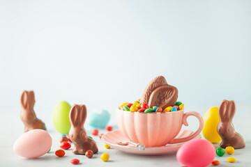 Rabbit chocolate ears and colored dragee sweets in a cup on the table. Easter concept. Copy space