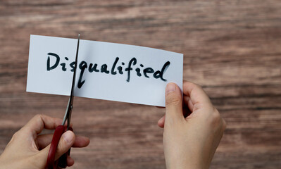Scissors cutting word disqualified on paper