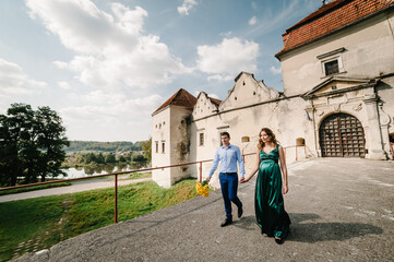 Fototapeta na wymiar Happy couple: a young beautiful pregnant wife in a long dress and husband walking together on a sunny summer day. Man and woman in love.