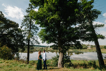 Photo of pregnant happy woman and cheerful man in park. Romantic moments pregnant. Couple walking in nature.