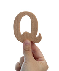 Hand holding wooden letter Q