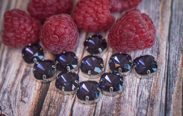 Rhinestones of various sizes and shapes are fixed in goats of gold and silver color, photographed on a wooden board of neutral color.