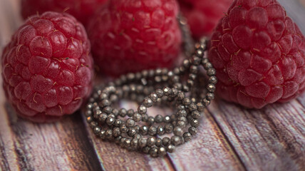 The photo with pyrite stones is made on the background of a wooden board and raspberrys.
