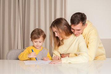 Adorable smiling family, parents in yellow clothes with their son painting