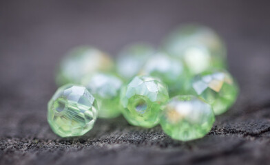 Glass beads of various shapes and sizes are photographed on a wooden board of neutral color.