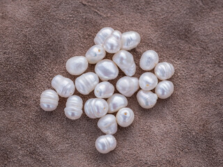Natural freshwater pearls of various shapes and colors are photographed on a wooden board and a...