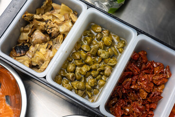 A kitchen counter with food on it including a bowl of salad and a bowl of vegetables.