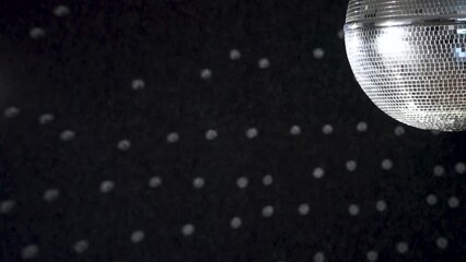 A spinning mirrored disco ball reflects light onto the wall. - Powered by Adobe