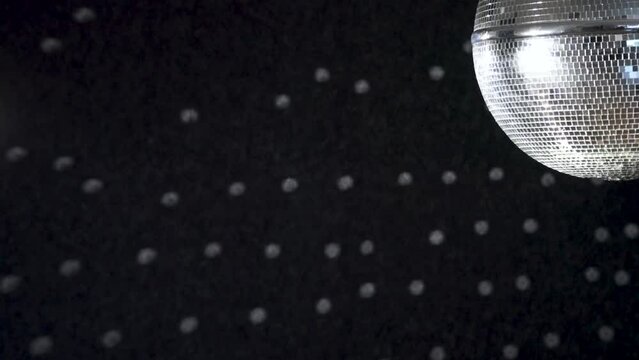 A spinning mirrored disco ball reflects light onto the wall.