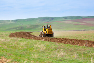 Traktok plows the land, preparing for sowing seeds. Industrial agriculture and farming. Tractor driver at work in the field. Harvesting, harvester harvests.