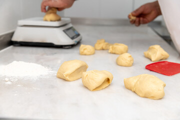 Cook weighing hamburger bun dough on scale on marble counter