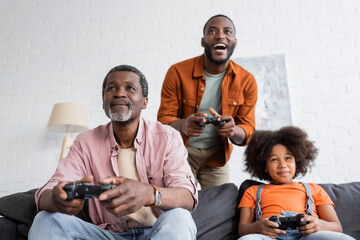 KYIV, UKRAINE - JULY 17, 2021: African american grandfather playing video game with family