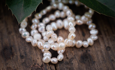 Natural freshwater pearls of various shapes and colors are photographed on a wooden board and a...