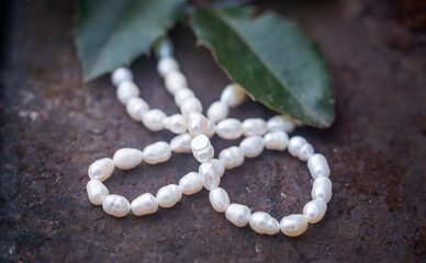 Natural freshwater pearls of various shapes and colors are photographed on a wooden board and a...