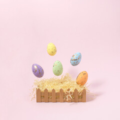 Easter basket with colorful flying  eggs on a pink background. Creative concept.