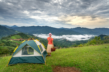 Nam Tra My District, Quang Nam Province, Vietnam - Female tourist with her tent camping on the top of a mountain, a valley of white clouds floating in the early morning. 