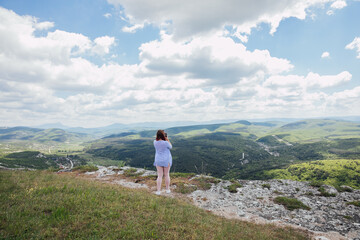 Obraz premium a woman on the mountain looks into the distance admiring nature journey hiking