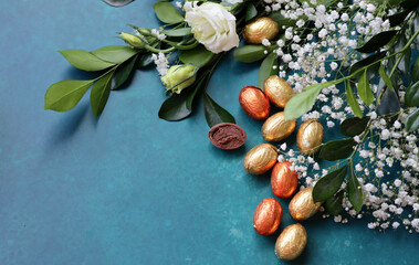 Foil wrapped Easter chocolate eggs in a glass bowl. Easter celebration concept. Colorful still life with sweets. Textured background with copy space. Easter greeting card. 