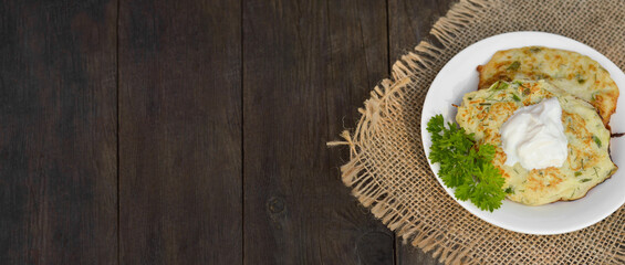 Zucchini pancakes with parsley on a wooden table. Vegetarian food