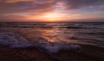 Sunset over the sea shore, sandy beach, colorful sky