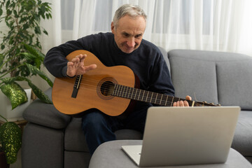 an elderly man learns to play the guitar on a laptop