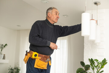 Electrician installs lamp lighting and spot loft style on ceiling
