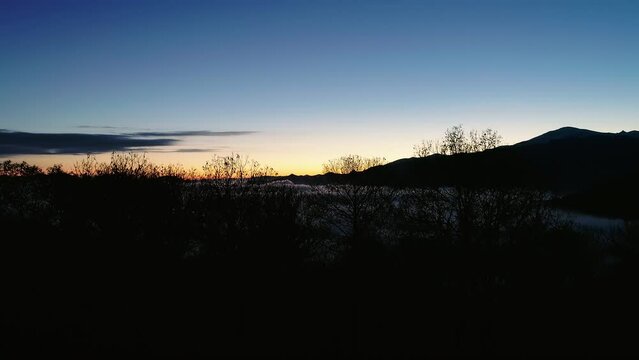 Flying over the trees at dawn to reveal the low hanging clouds covering the valley below