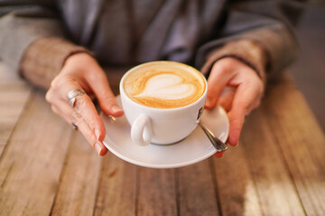 Hot art Latte Coffee in a cup on wooden table and Coffee shop blur background with bokeh image