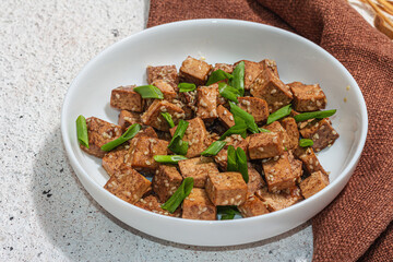 Fried teriyaki Tofu with scallions and sesame seeds. Healthy vegan meatless meal rich in protein