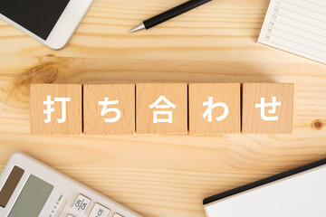 打ち合わせと書かれたブロック、電卓、スマホ、ノート、カレンダー