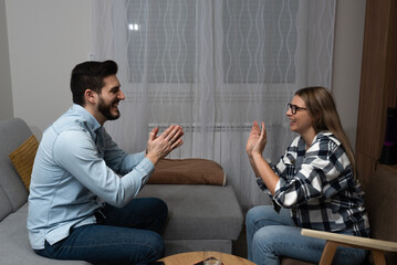 Couple having fun at home playing pantomime game, explaining, acting and guessing. Friends...