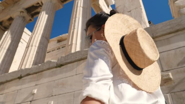 Young Woman visiting Parthenon, Acropolis of Athens, Greece. Large hat, fashion white dress, sunglasses, vintage camera.