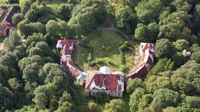 An unmanned aerial vehicle is hovering above an abandoned yet stunning architectural estate engulfed by forestation