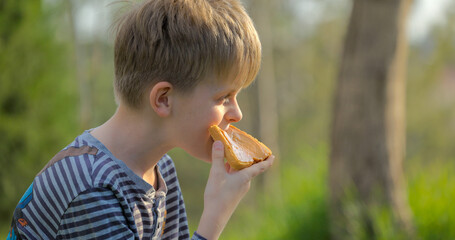 Boy eating sandwich with peanut butter in the park