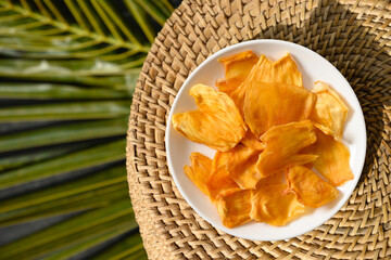 Jackfruit chips in white plate on tropical background with leaf. Vegan sugar free fruits chips for...