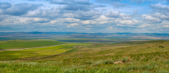 Bald Mountain in the Buryat Republic of Russia. Green hills against a blue sky with clouds.