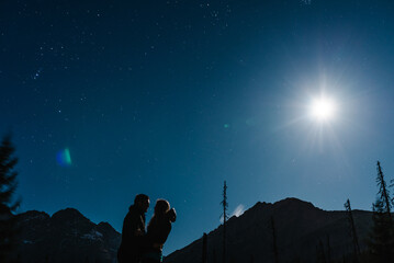 Couple, man and girl together, under the stars, holding hands and kissing. Inspiration. Night mountains.