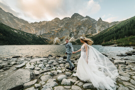 The bride and groom near the lake in the mountains. A couple together against the backdrop of a mountain landscape. Morskie Oko (Sea Eye) Lake. Tatra mountains in Poland.